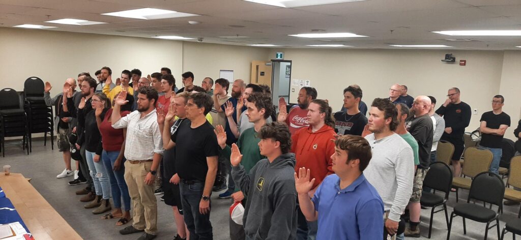 A room filled with new IBEW Local 625 Members, raising their right hands, swearing into IBEW membership.